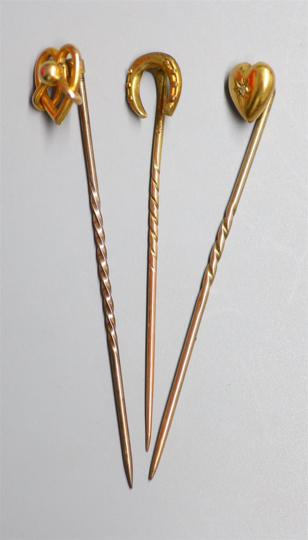 Three assorted Edwardian yellow metal stick pins, one set with diamond chip, 59mm et infra, gross 3.2 grams.